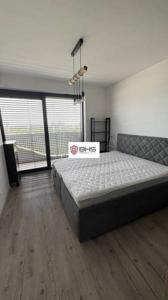 Spálňa s veľkou posteľou a podlahou s dreveným dekorom v 2-izbovom byte.