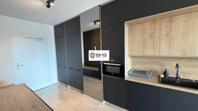 Kuchyňa s čiernymi a drevenými skrinkami, podlaha s dreveným dekorom v 2-izbovom byte.