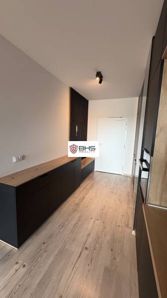 Chodba s bielymi stenami a čiernym nábytkom v 2-izbovom byte, podlaha s dreveným dekorom.