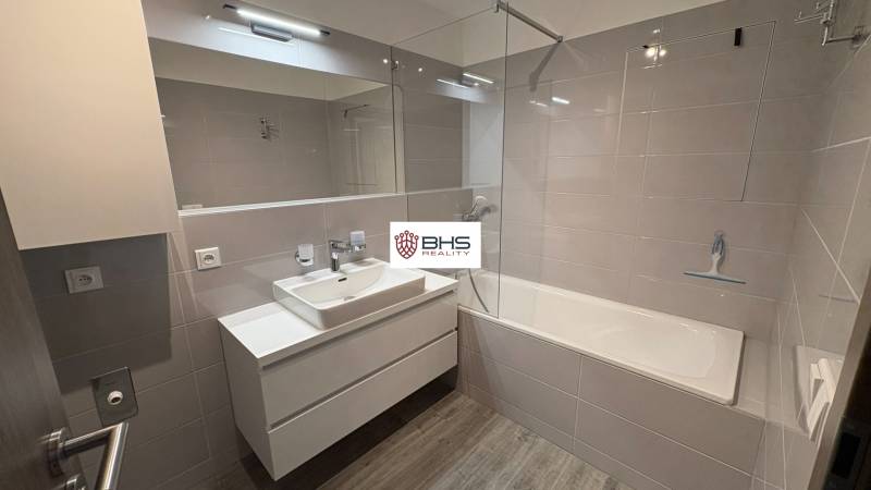 Kúpeľňa v 2-izbovom byte s umývadlom, vaňou a podlahou s dreveným dekorom.