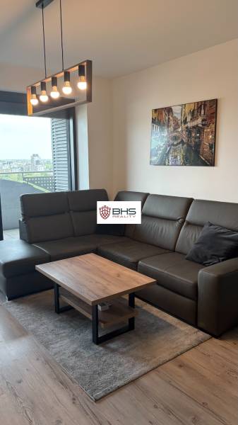 Obývacia miestnosť s koženou sedačkou, stolíkom a lampou v 2-izbovom byte.