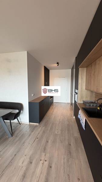 Kuchyňa v 2-izbovom byte s podlahou s dreveným dekorom a tmavým nábytkom.