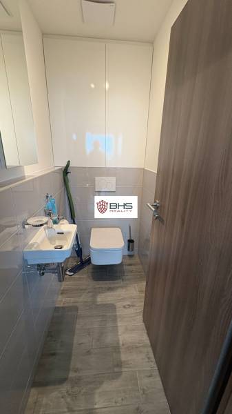 Kúpeľňa v 2-izbovom byte s umývadlom, toaletou a podlahou s dreveným dekorom.