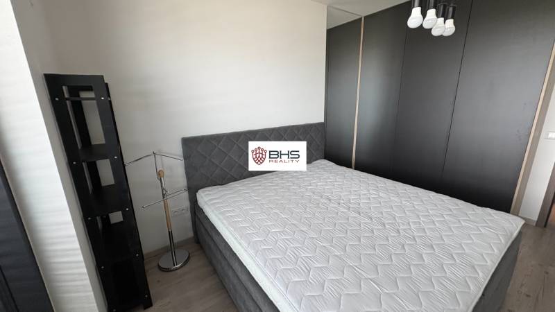 Spálňa s veľkou posteľou, moderným osvetlením a skriňou v dvojizbovom byte.